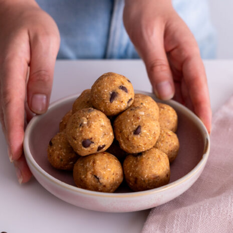 Close-up of chickpea cookie dough bliss balls stacked on a plate.