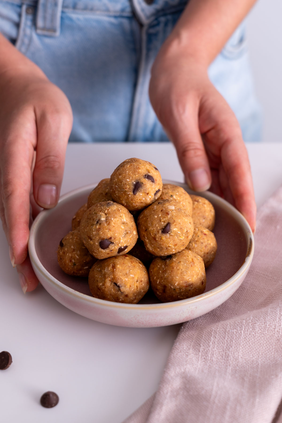 Close-up of chickpea cookie dough bliss balls stacked on a plate.