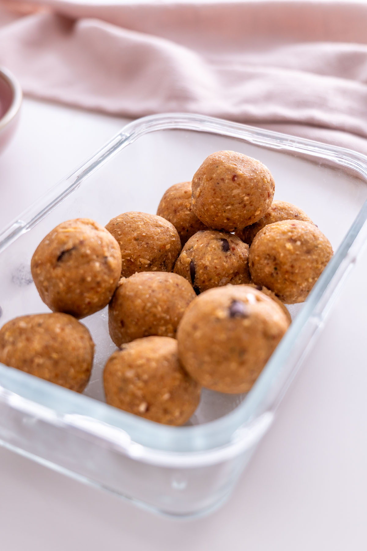 Chickpea cookie dough bliss balls in a glass meal prep container for storage.