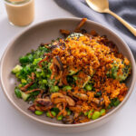 Close-up of crispy rice salad with gochujang mushrooms, cucumber, avocado, and edamame in a bowl.
