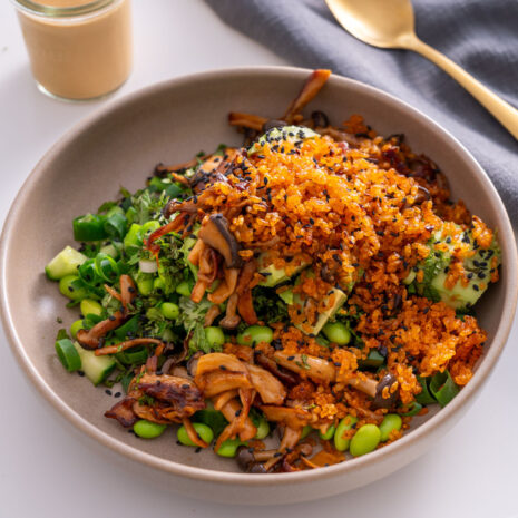 Close-up of crispy rice salad with gochujang mushrooms, cucumber, avocado, and edamame in a bowl.