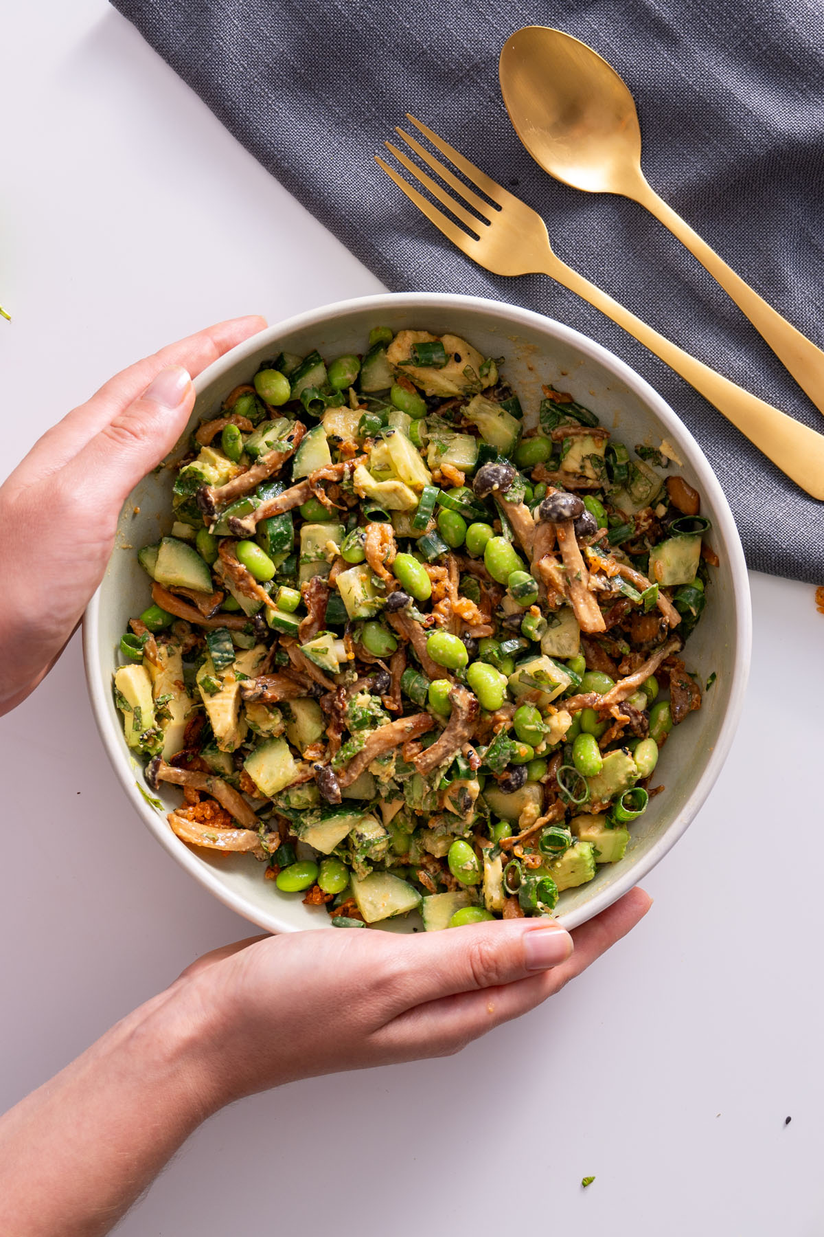 Sarah Cobacho holding a mixed bowl of crispy rice salad with vegetables and mushrooms.