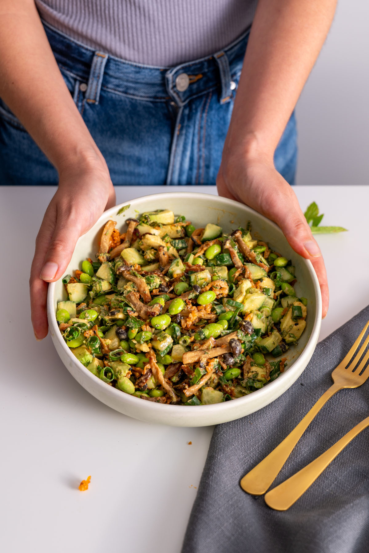 Sarah Cobacho holding a bowl of crispy rice salad with gochujang mushrooms, avocado, and edamame.
