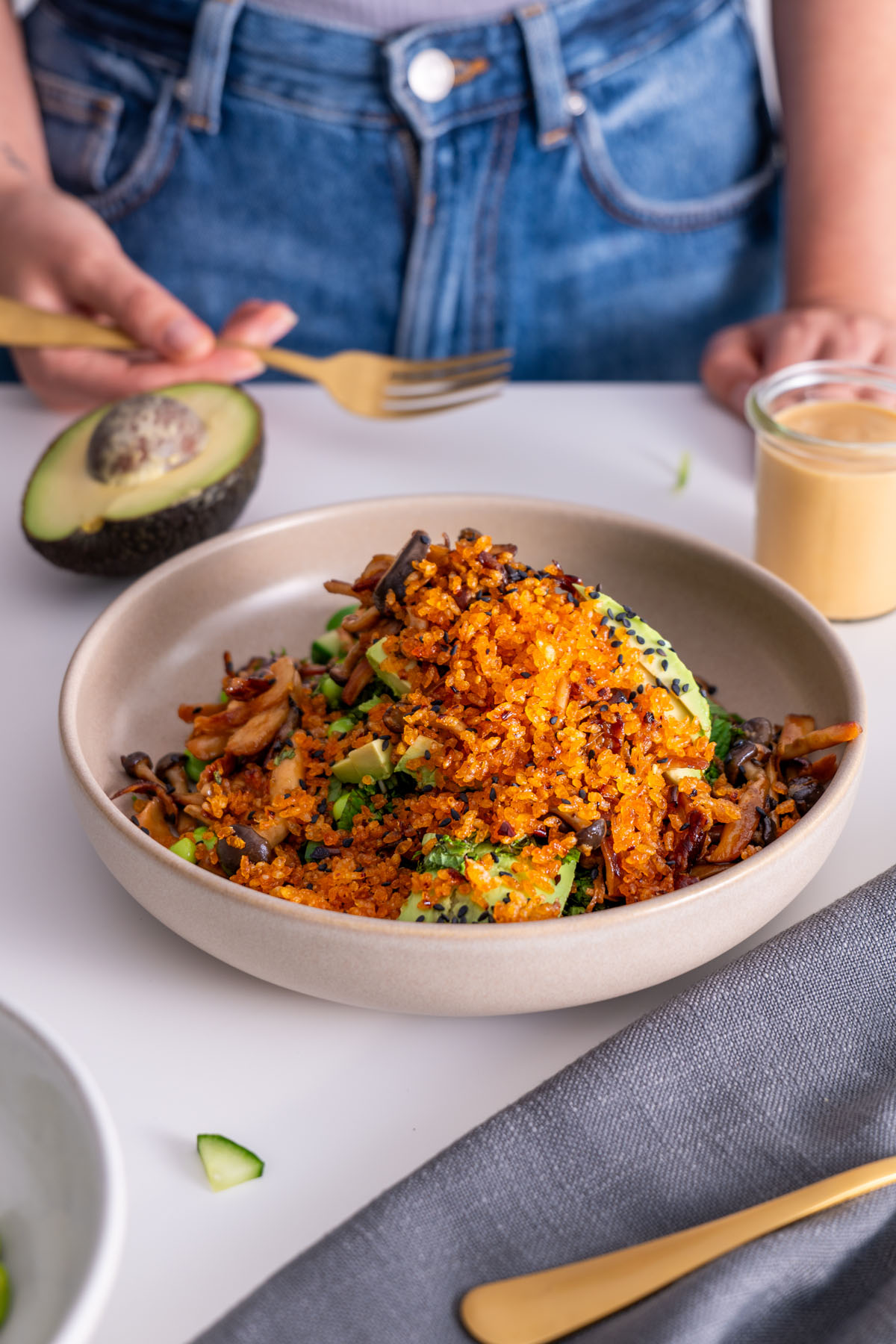 Crispy rice salad with gochujang mushrooms served in a bowl with peanut sauce in the background.