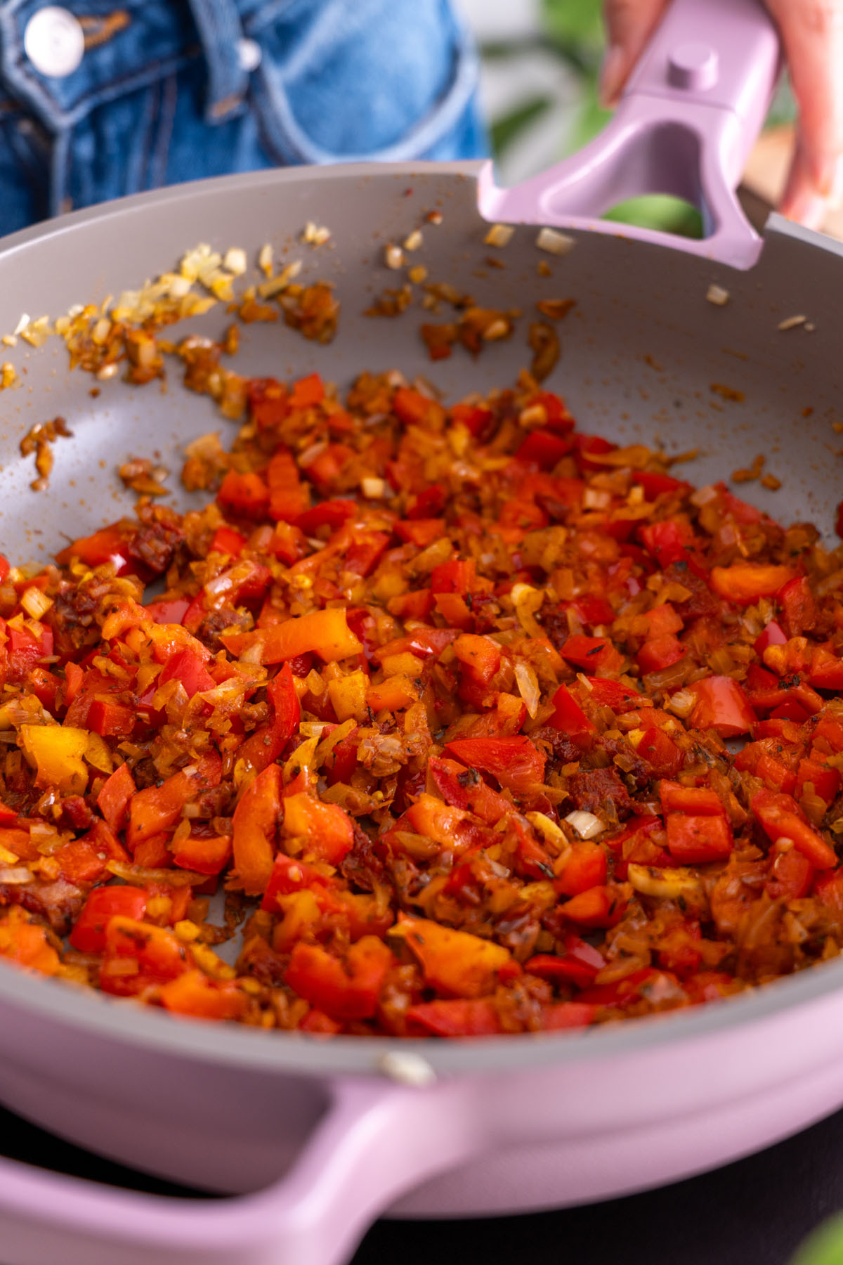 A close-up shot of sautéed red peppers and onions in a purple Always Pan.