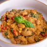 Close-up of a bowl of creamy orzo with butter beans topped with fresh basil.