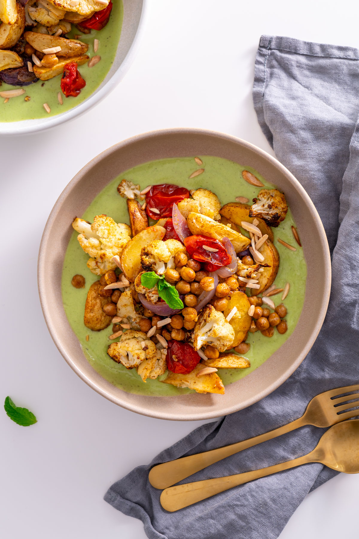 A serving of curry baked veggies with raita sauce, topped with mint and slivered almonds.