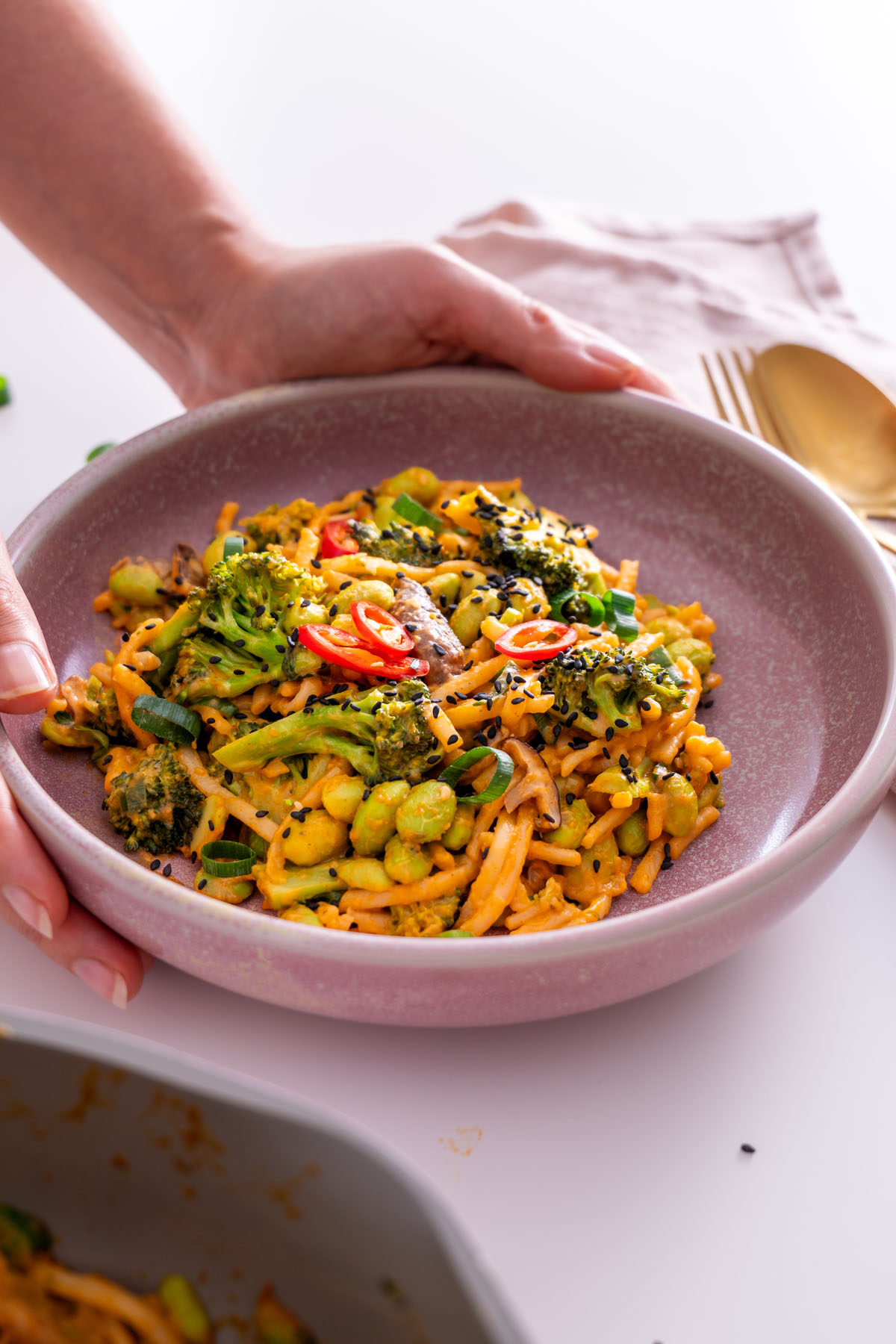 Sarah Cobacho holding a bowl of peanut gochujang noodles.