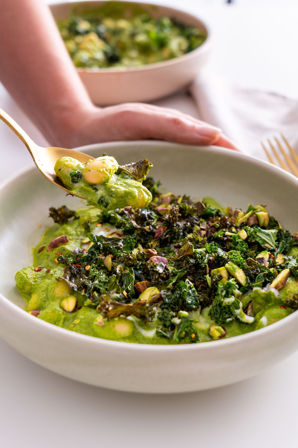 Close-up of a spoonful of Super Green Butter Beans with crispy kale and pistachios