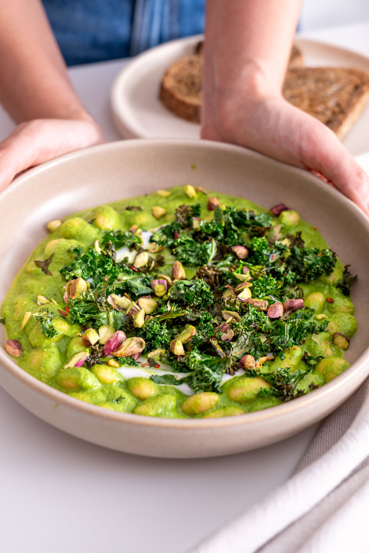 Final plated dish of Super Green Butter Beans with pistachios and crispy kale garnish