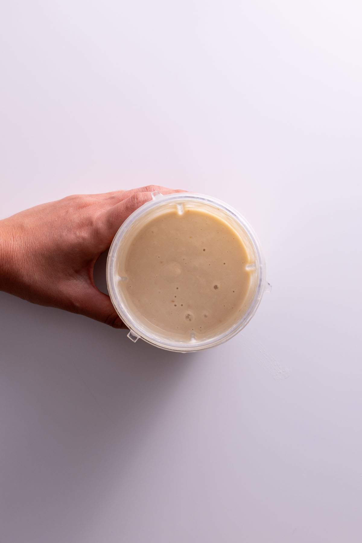 Sarah Cobacho holding a cup of creamy white bean spread with roasted garlic.