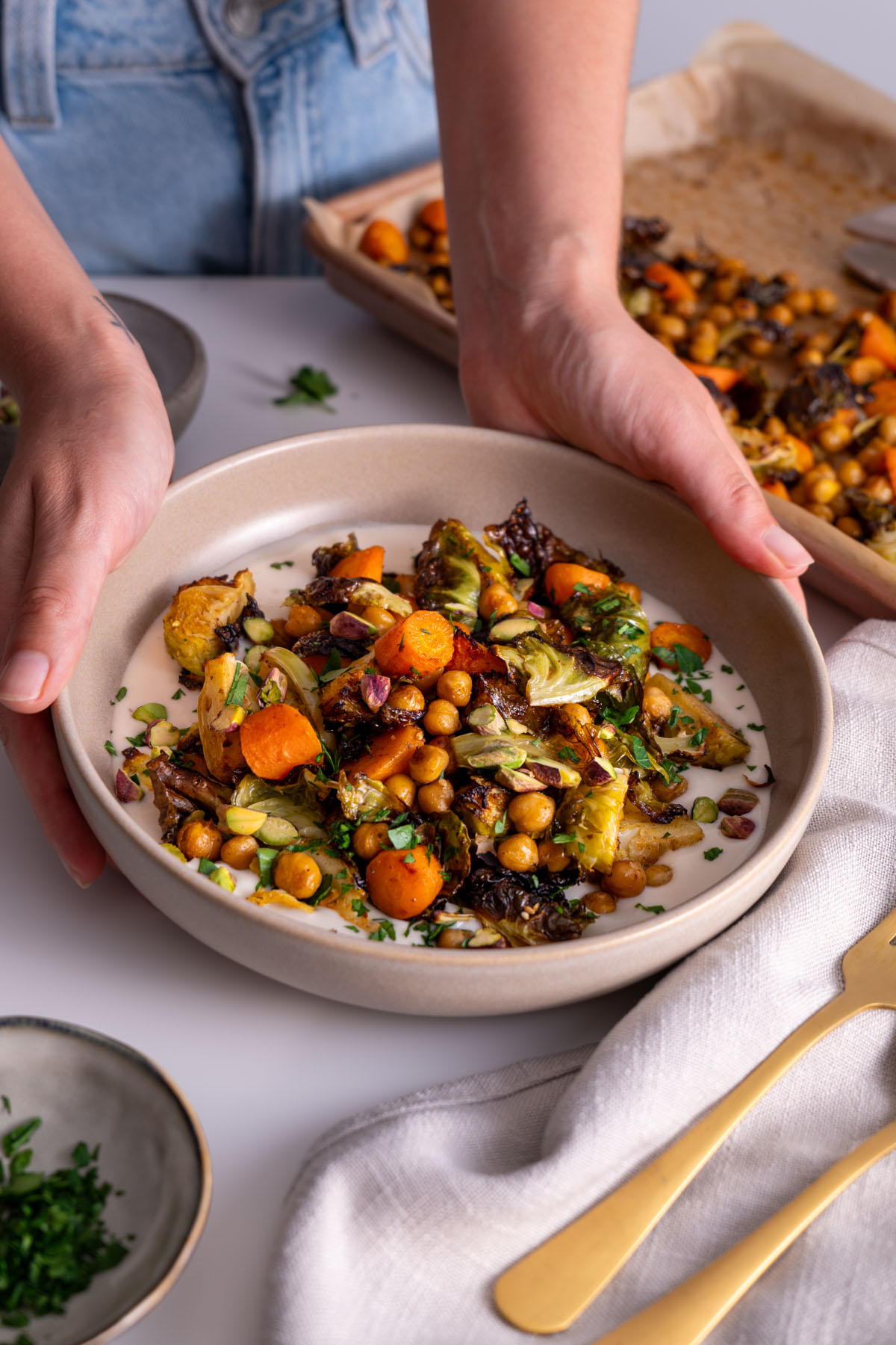 Close-up of plated Sweet & Spicy Roasted Veggies on a White Bean Spread garnished with coriander and pistachios.