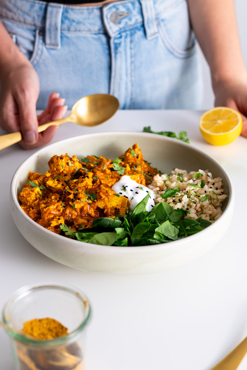 Freshly made vegan butter chicken with tofu, topped with cilantro and served with greens and brown rice.