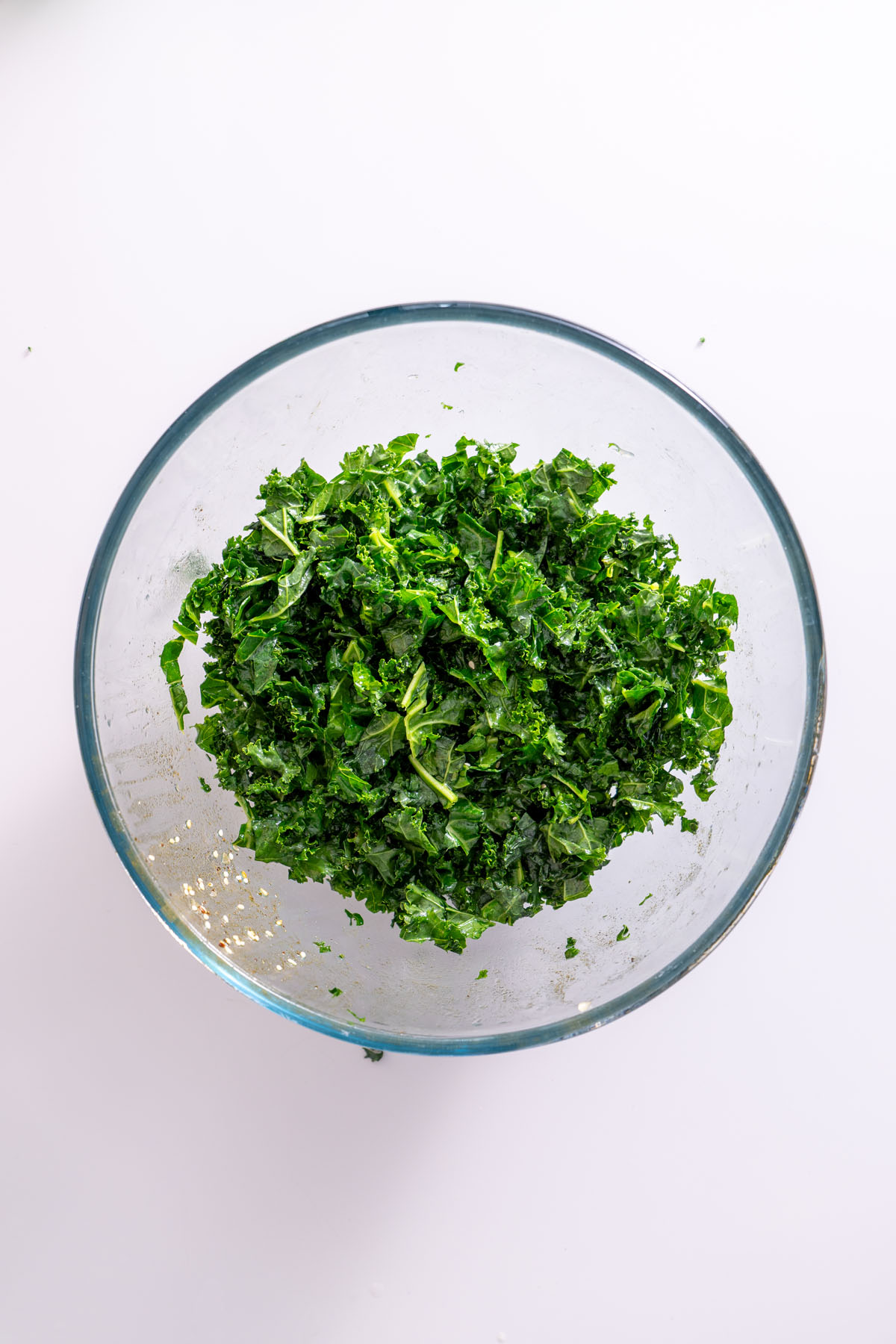 Massaged kale in a glass bowl, ready to be added to the bowl.