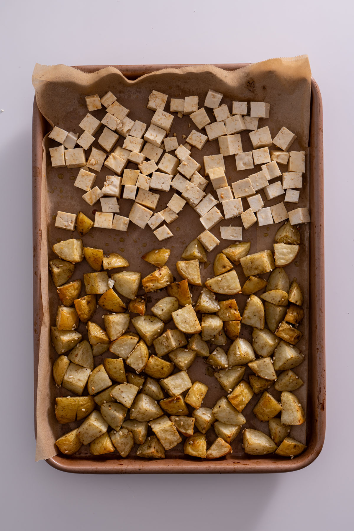 Cubes of tofu and diced potatoes on a baking sheet, ready for roasting.