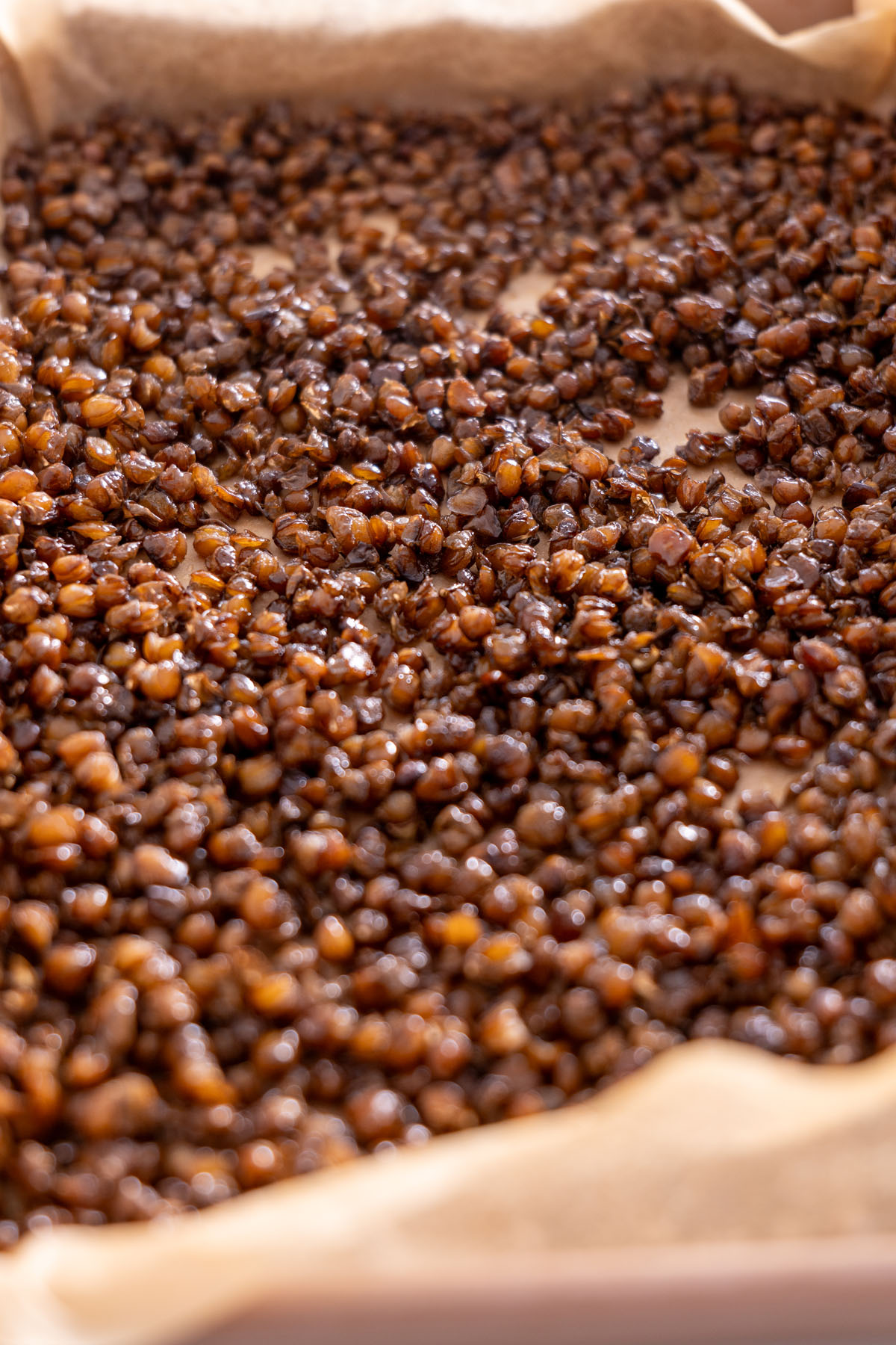 Close-up of crispy roasted lentils on a baking sheet, showing texture and color.