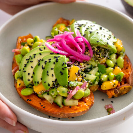 Close-up of roasted sweet potato with avocado, edamame, mango, and other fresh toppings in the Edamame Sweet Potato Bowl.