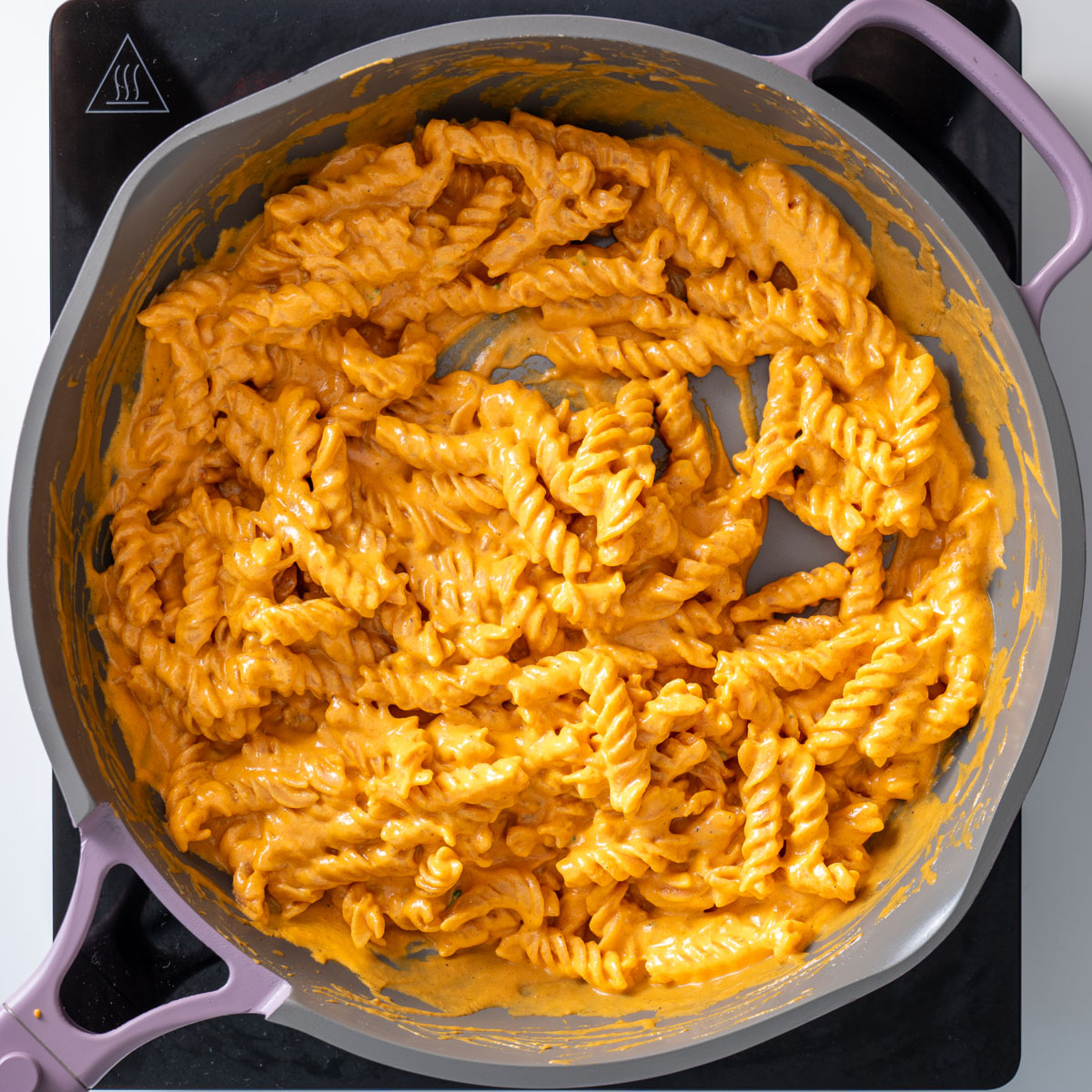 Close-up of creamy romesco pasta coated with sauce in a pan.