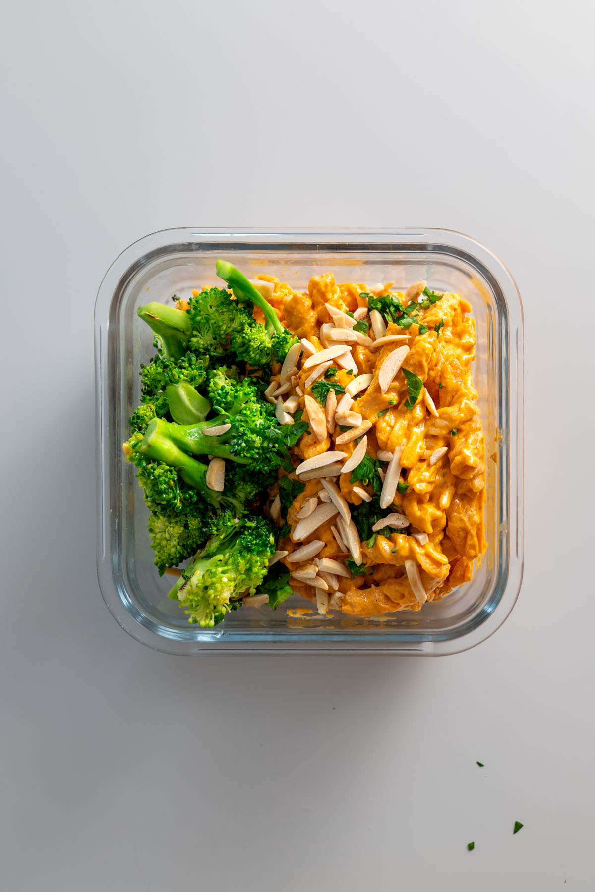 Meal-prepped romesco pasta and broccoli in a glass container, ready for storage or serving.