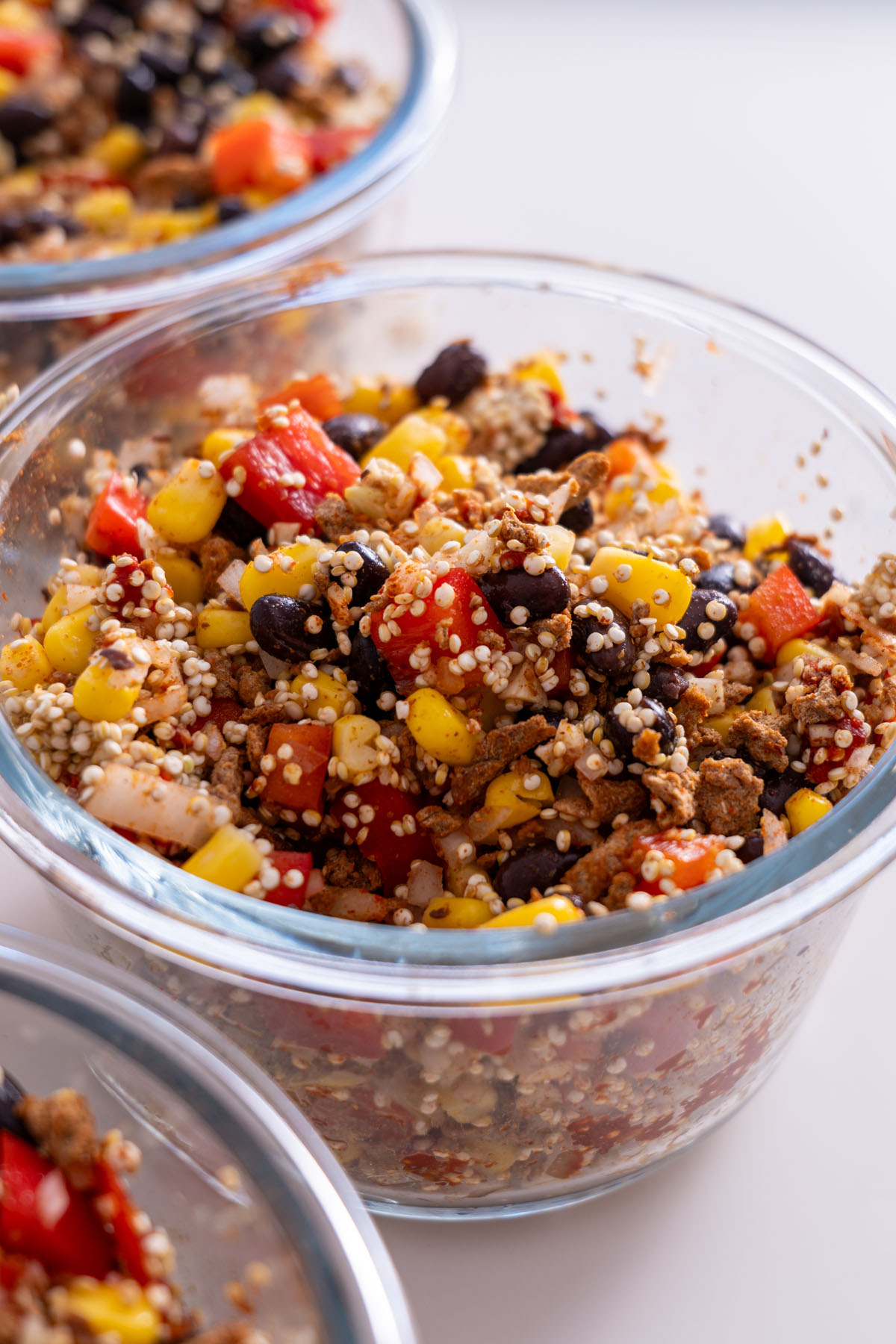 Close-up of burrito bowl ingredients including black beans, corn, quinoa, and red bell pepper, showing texture.