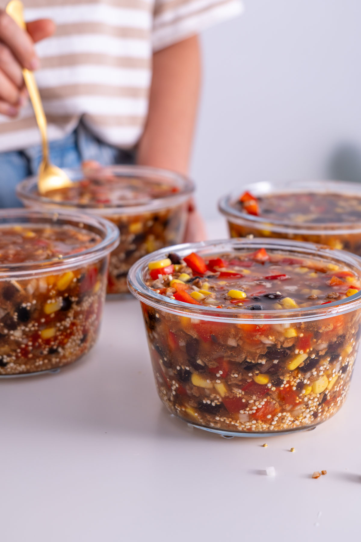Sarah Cobacho holding a glass bowl of oven-baked burrito bowl ingredients before baking.