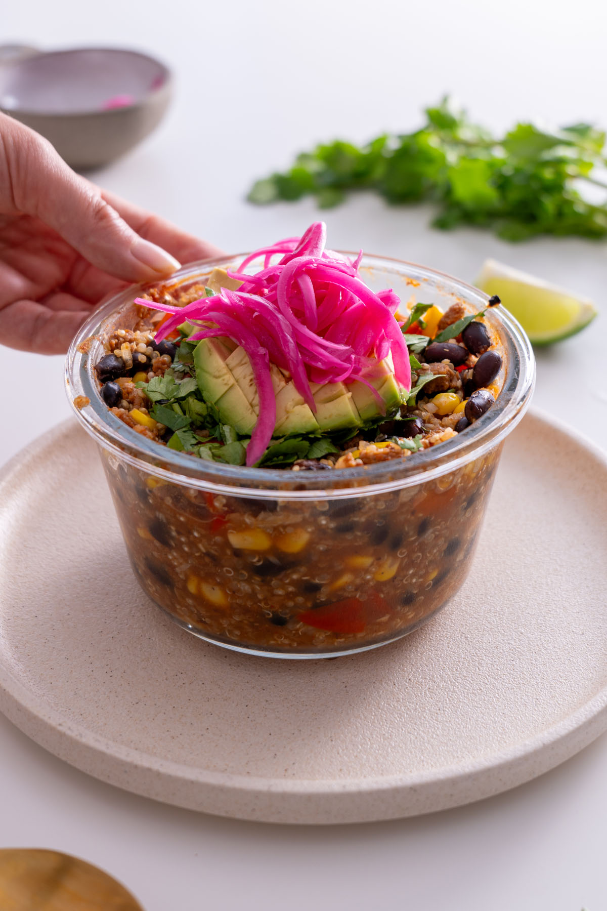 Close-up of an oven-baked burrito bowl with colorful toppings including avocado, pickled onions, and cilantro.