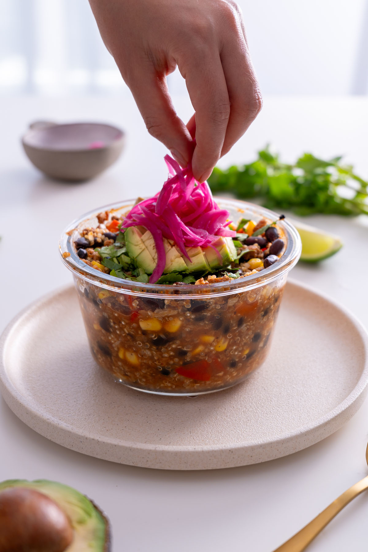 Sarah Cobacho adding pickled onions to the finished oven-baked burrito bowl for a vibrant topping.