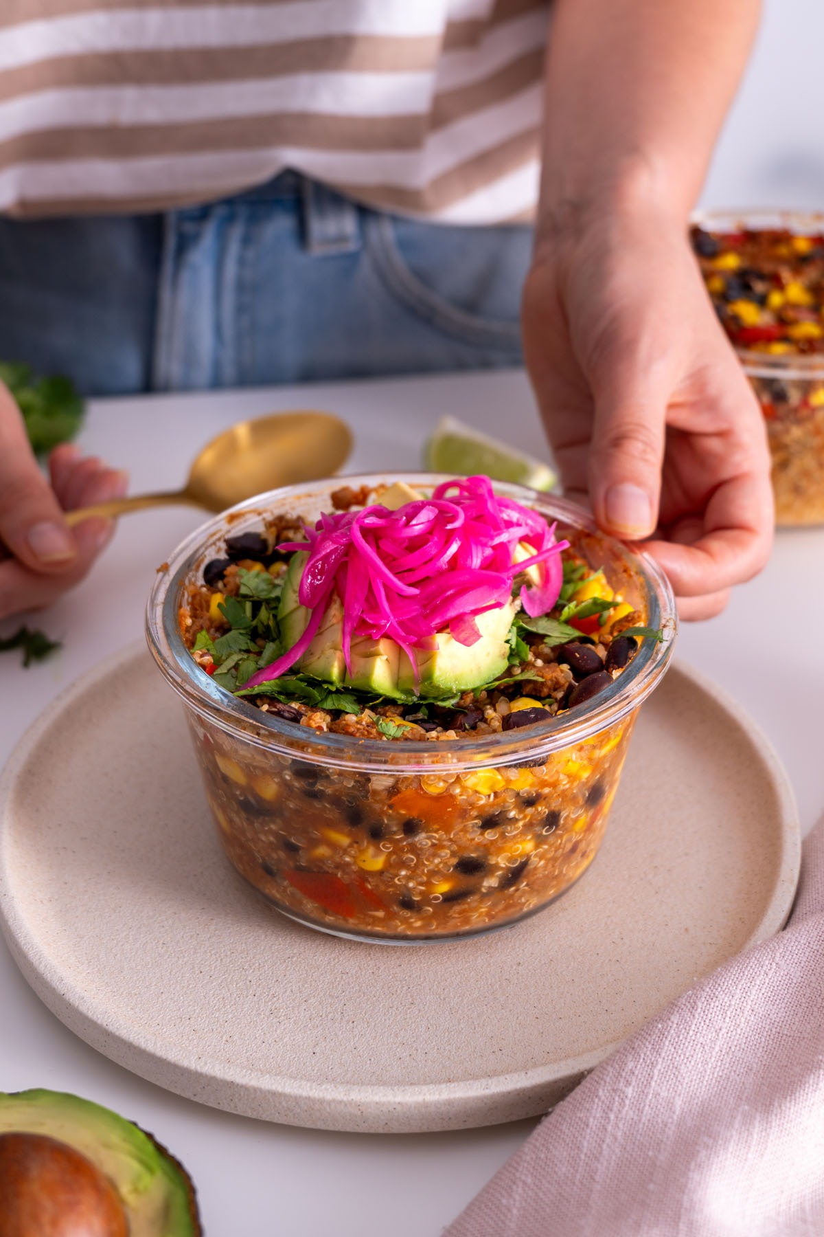 Sarah Cobacho placing an avocado-topped burrito bowl on a plate, showing final presentation.