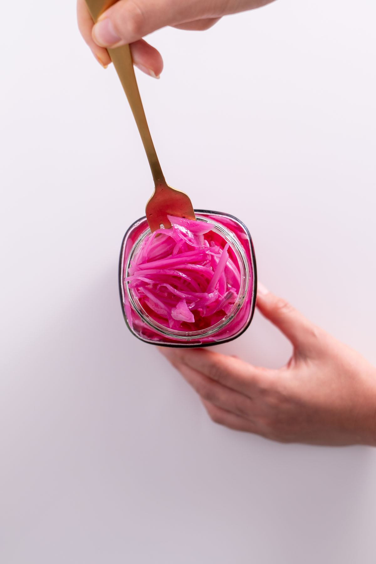 Sarah Cobacho holding a jar of pickled red onions with a fork in the jar.