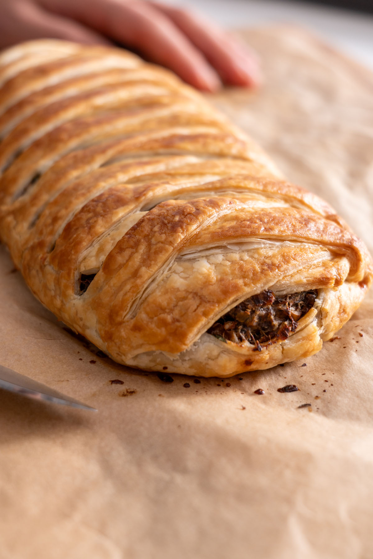 Freshly baked vegan mushroom Wellington with a golden crust on parchment paper.