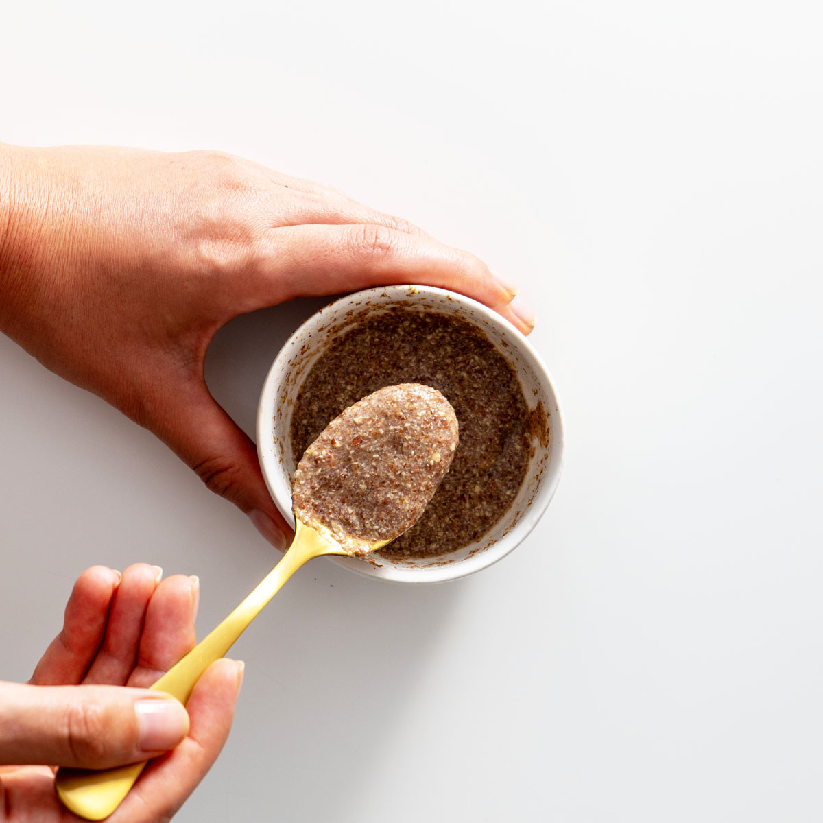 Sarah Cobacho holding a spoon of ground flaxseed mixture over a small bowl.