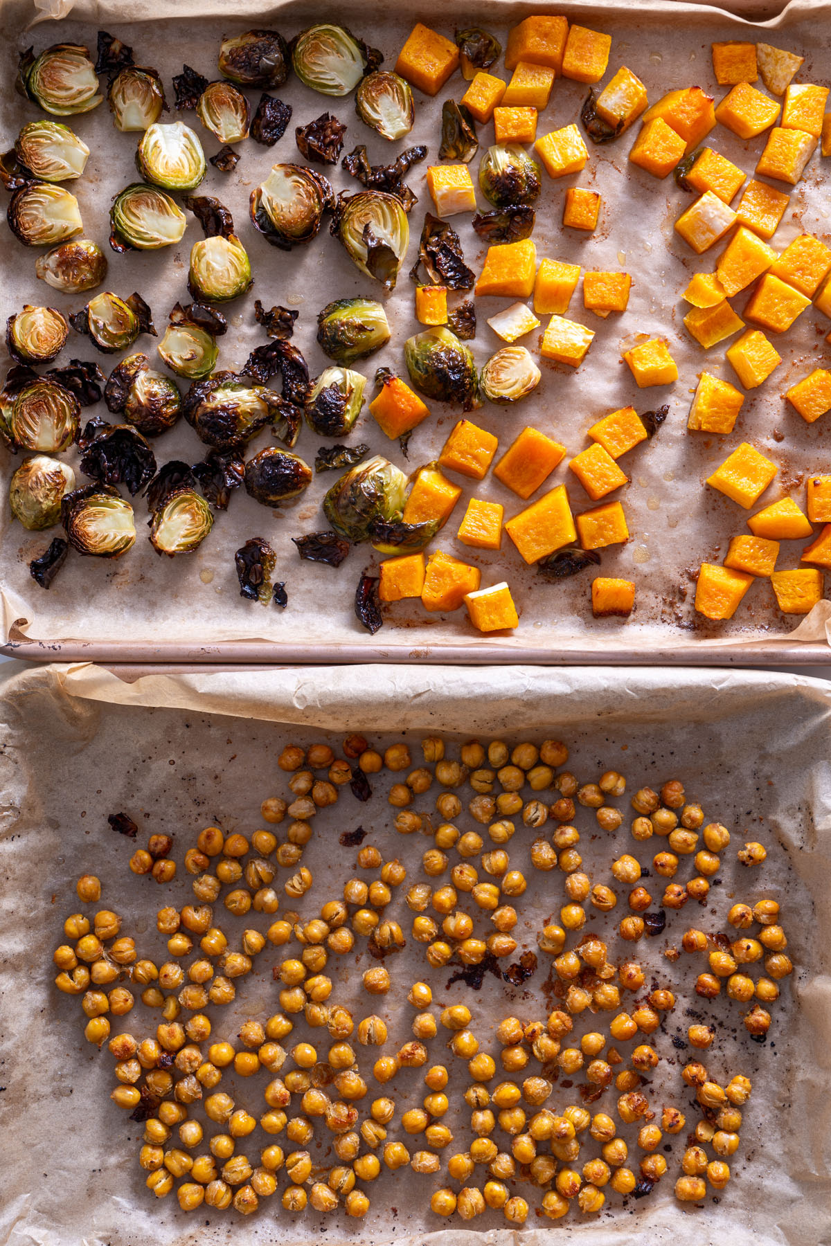 Roasted Brussels sprouts, chickpeas, and butternut squash on a lined baking sheet.