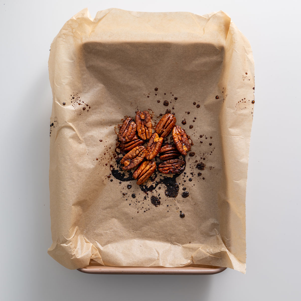 Maple-glazed roasted pecans on parchment paper for a fall salad recipe.