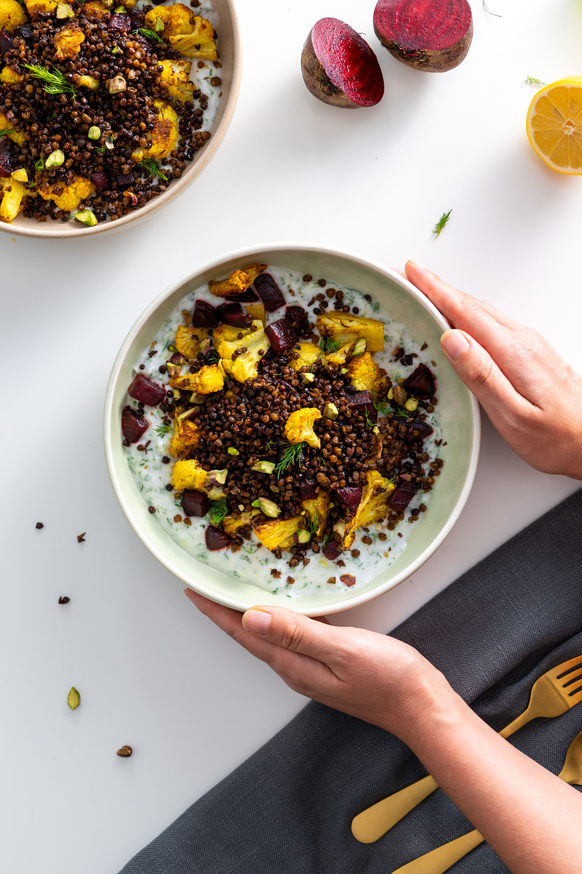 Sarah Cobacho holding a bowl of roasted cauliflower, lentils, and tzatziki with a lemon in the background.