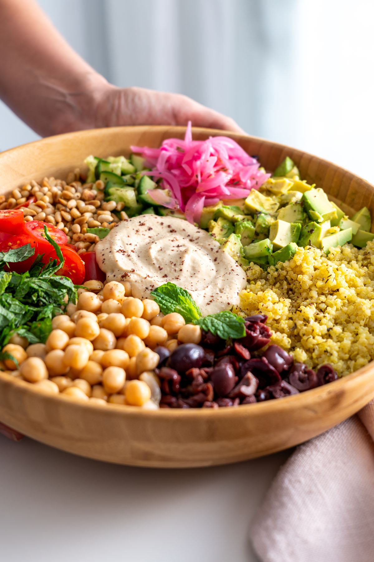 Close-up of a colorful Mediterranean salad with quinoa, chickpeas, and fresh vegetables in a wooden bowl.