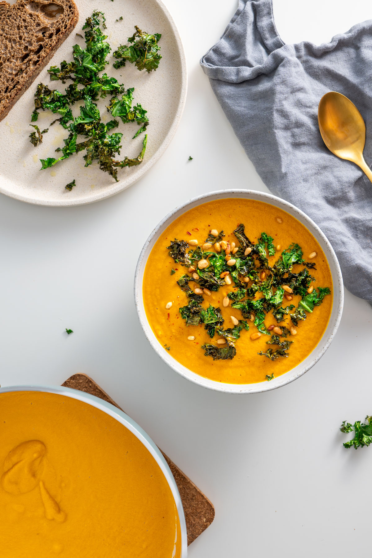 Table setting with roasted vegetable soup, crispy kale, and bread.