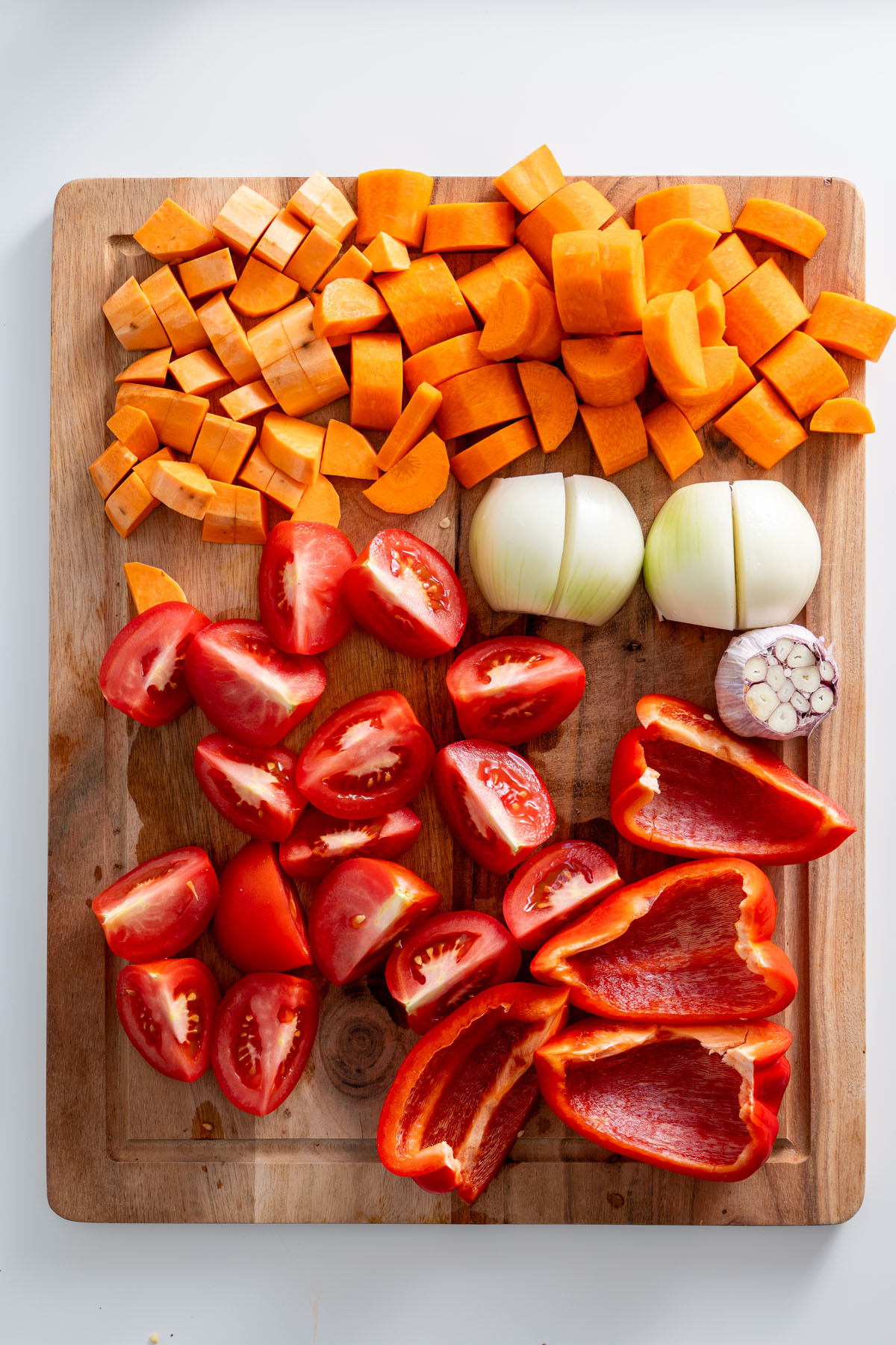 Chopped vegetables for roasted vegetable soup on a cutting board.
