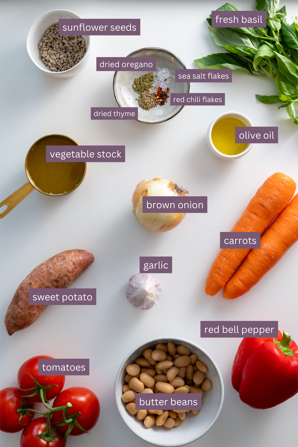 Vibrant ingredients for roasted vegetable soup on a white surface.