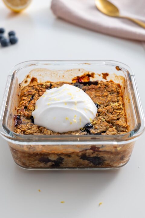 Close-up of baked blueberry oats topped with a dollop of coconut yogurt and lemon zest.