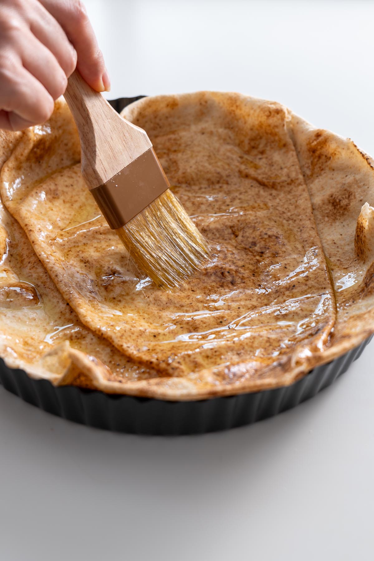 A golden-brown pita bowl brushed with olive oil before baking.