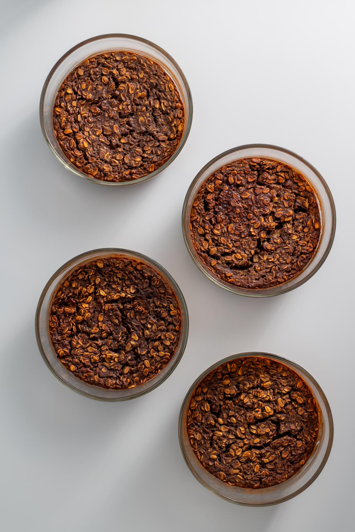 Four glass dishes of fully baked tiramisu oats with a golden brown top
