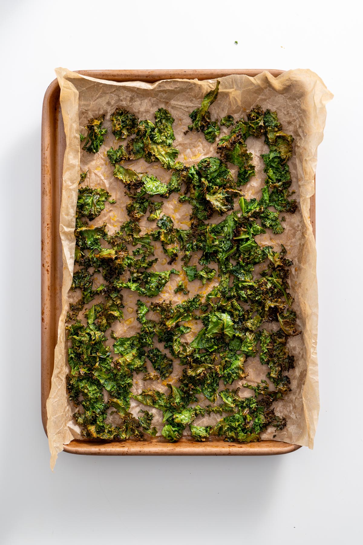 Crispy kale on a baking tray lined with parchment paper.