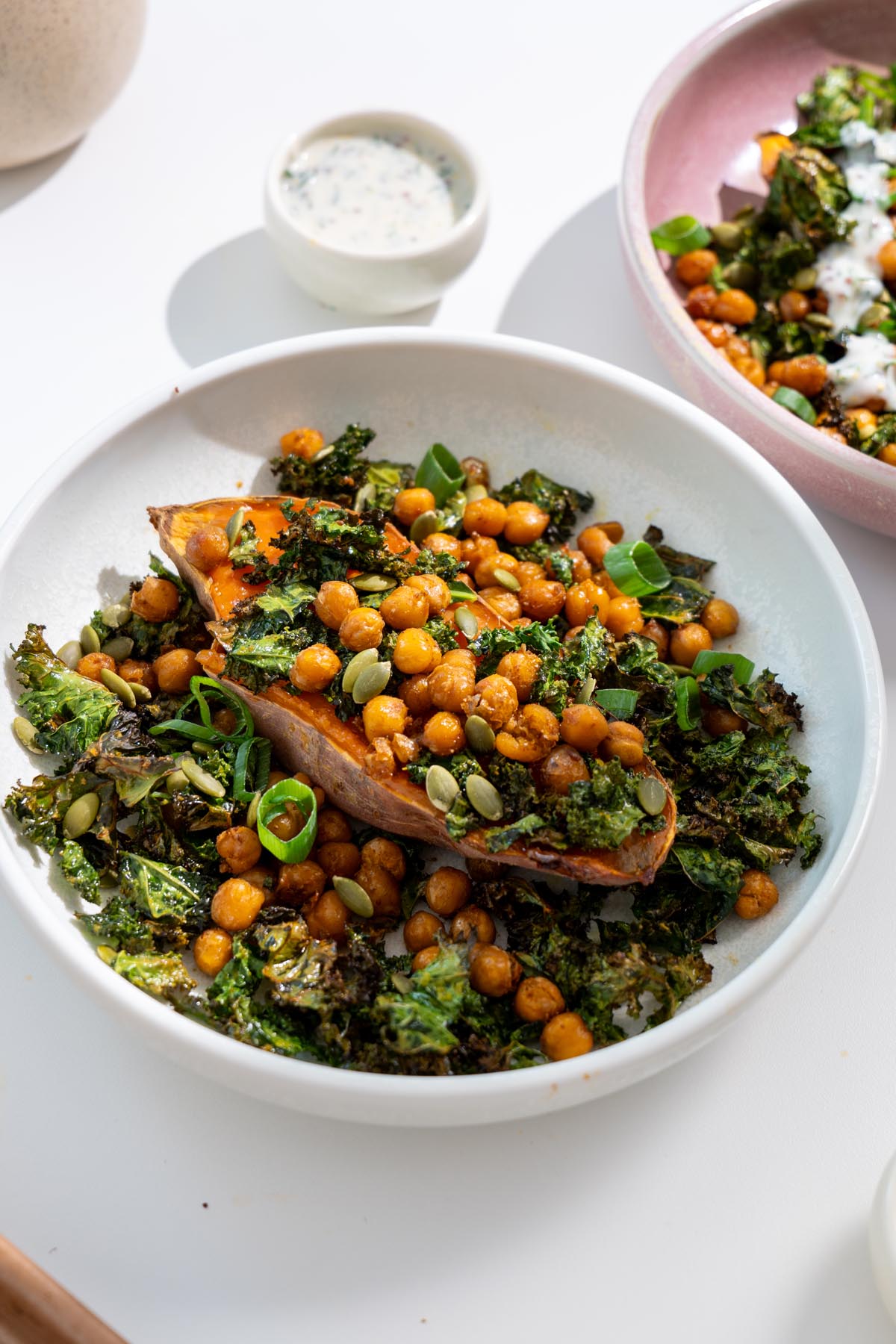 Bowl of roasted sweet potato, crispy kale, and chickpeas without sauce on a white plate.