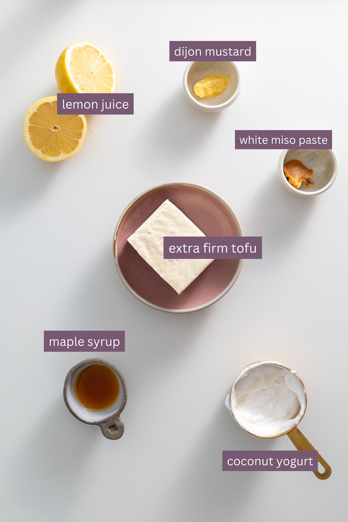 Vibrant ingredients for the whipped tofu dressing, including tofu, lemon, and coconut yogurt, on a white background.
