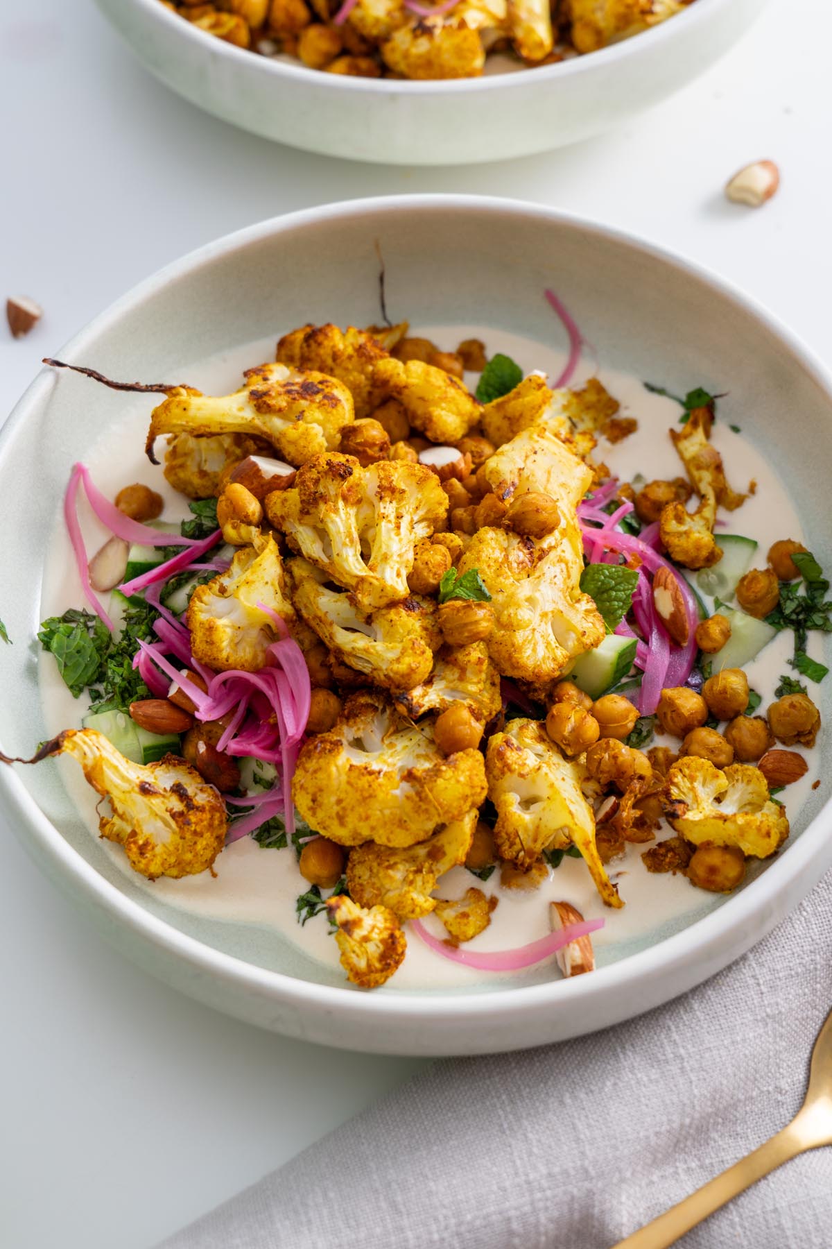A close-up of the tandoori spiced cauliflower bowl showcasing crispy chickpeas, roasted cauliflower, and fresh garnishes.