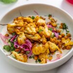A tandoori spiced cauliflower bowl served with chickpeas, pickled onions, and fresh herbs.