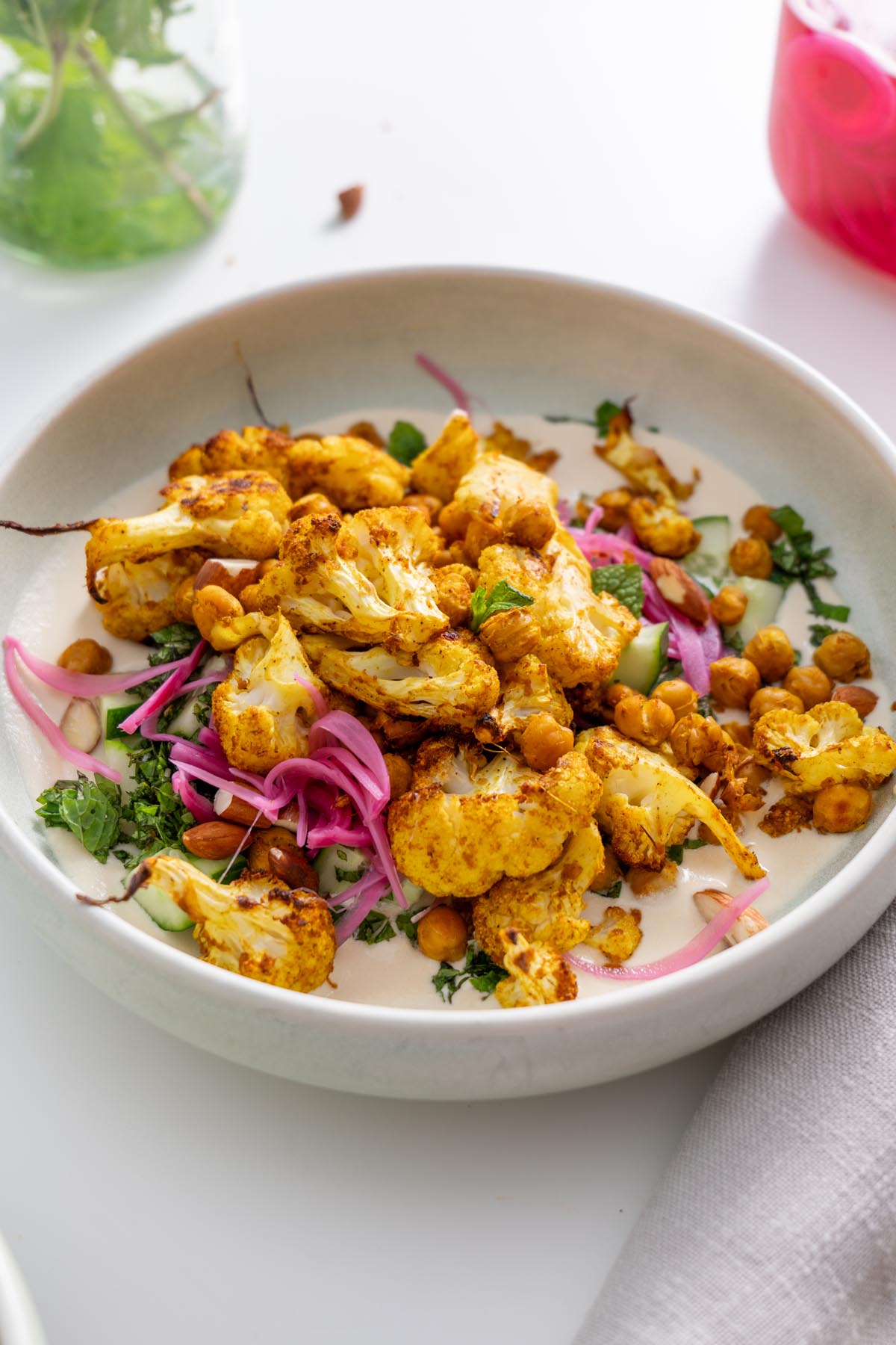 A tandoori spiced cauliflower bowl served with chickpeas, pickled onions, and fresh herbs.