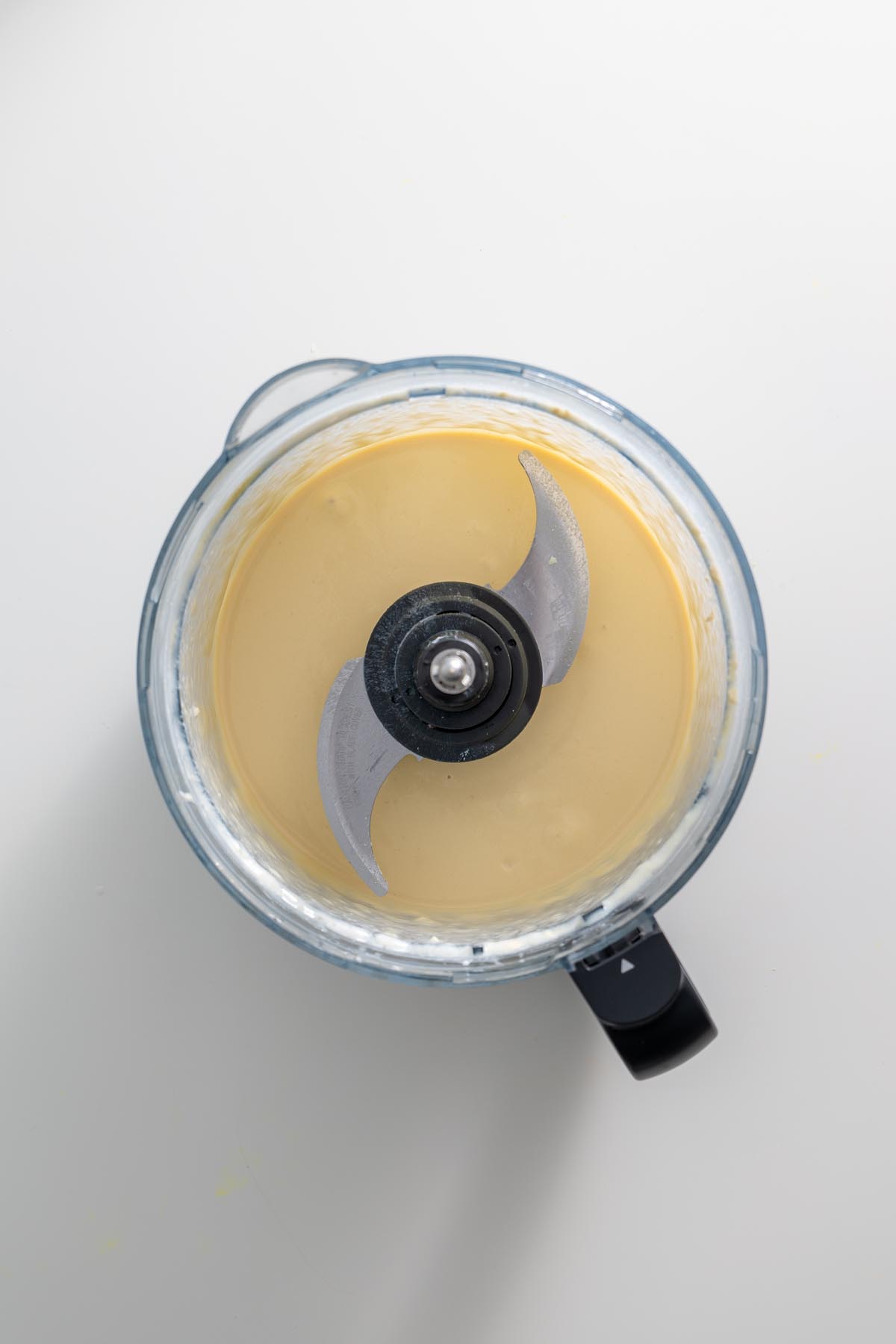 A creamy whipped tofu dressing in a food processor, smooth and ready to serve.