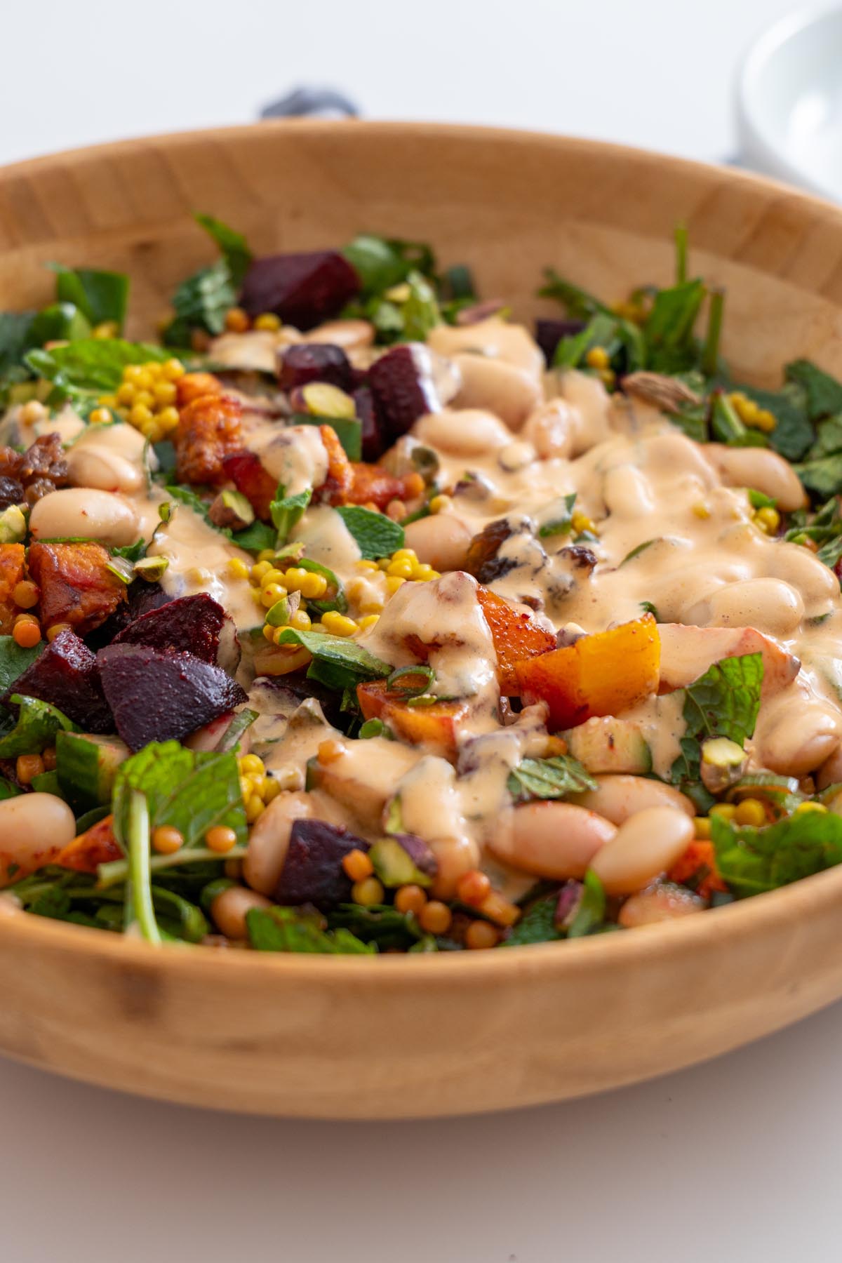Close-up of Moroccan Spiced Pearl Couscous Salad topped with creamy tahini dressing.