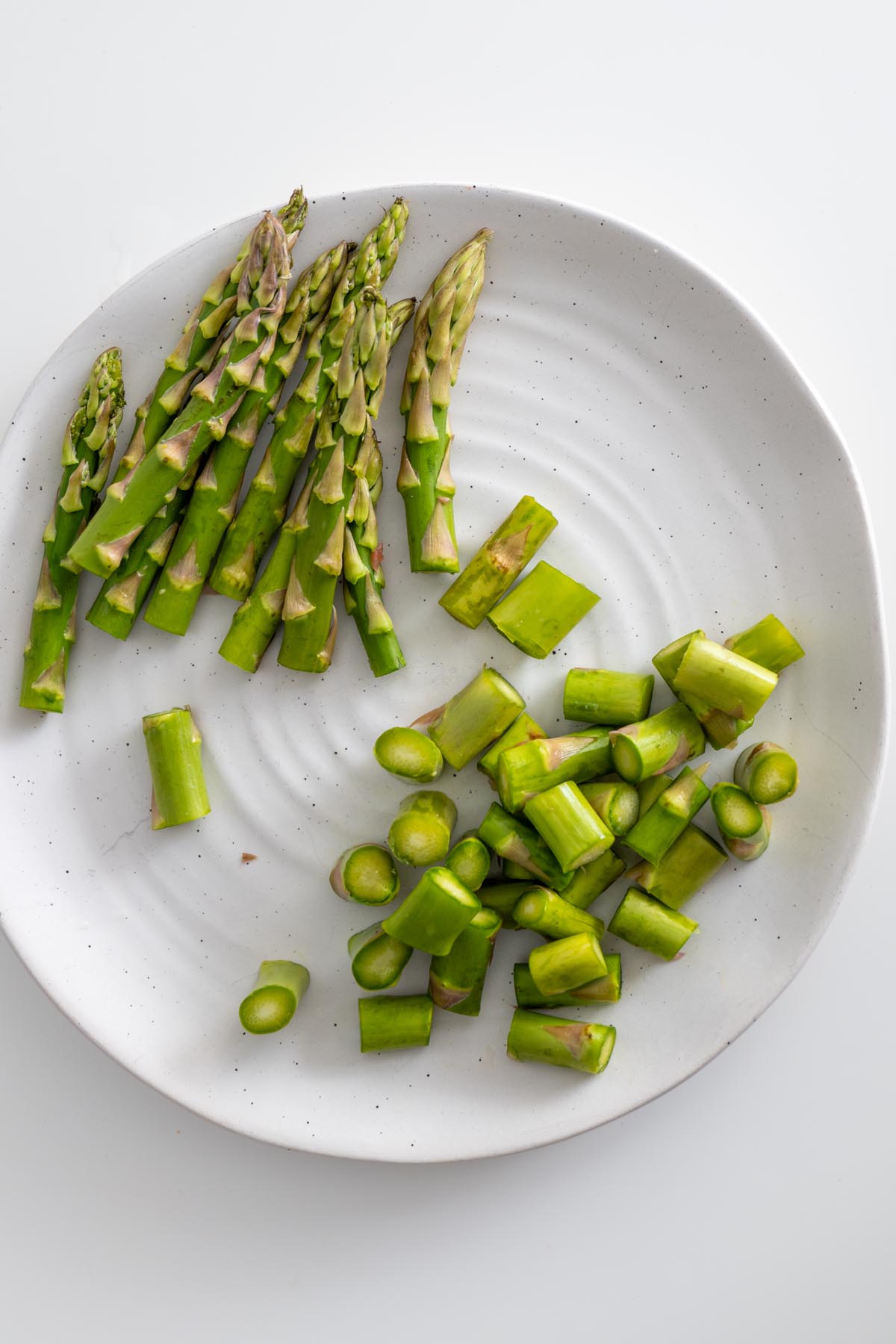 Raw and cooked asparagus laid out on a white plate
